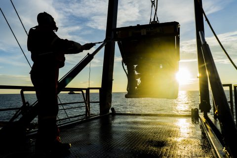 Photo silhouette of worker recovering robotics remote operated vehicle ROV after entering sea surface.